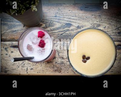 Top view of two alcoholic cocktails drinks on a rustic wooden bar  table, a pink smoothie with raspberries and an espresso martini  with coffee beans Stock Photo