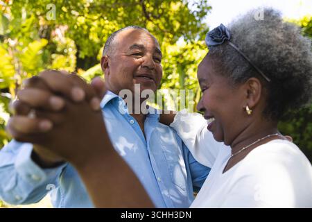 At wedding, Senior couple dancing joyfully in garden, enjoying sunny day together Stock Photo