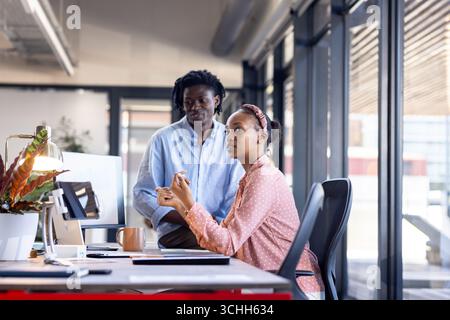 Collaborating at office desk, diverse colleagues discussing project with focus and engagement Stock Photo