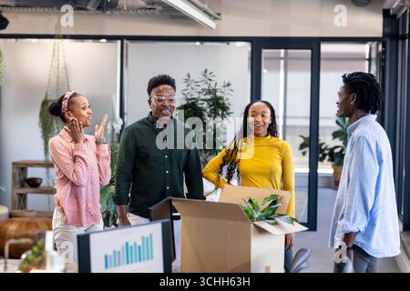 Diverse colleagues in office unpacking box, discussing new project with excitement Stock Photo