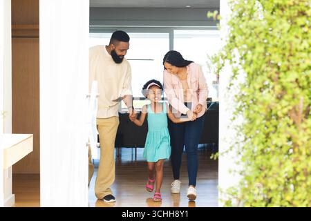 Happy family walking together at home, holding hands and smiling joyfully Stock Photo