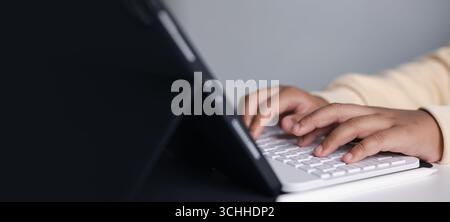 Close-up of hands typing on wireless keyboard connected to tablet. Concept of remote work, freelance job, online learning, digital lifestyle, modern o Stock Photo