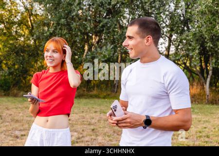 Young couple using smartphones while walking in park Stock Photo
