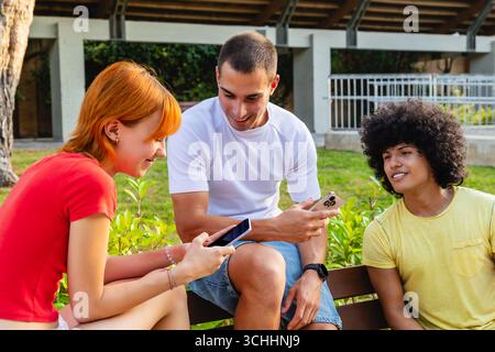 Group of young people using smartphones on bench Stock Photo