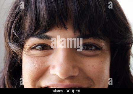 Smiling woman with dark hair looking directly at camera, showing happiness, at home Stock Photo