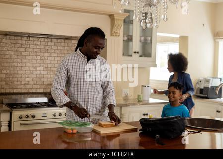 Father preparing lunch in kitchen while mother and son enjoy morning together Stock Photo