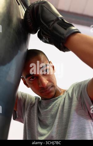 Asian man training on punching bag wearing black boxing gloves at boxing gym Stock Photo