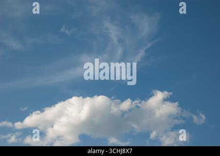 A blue sky with beautiful white clouds floating in soft daylight. Stock Photo