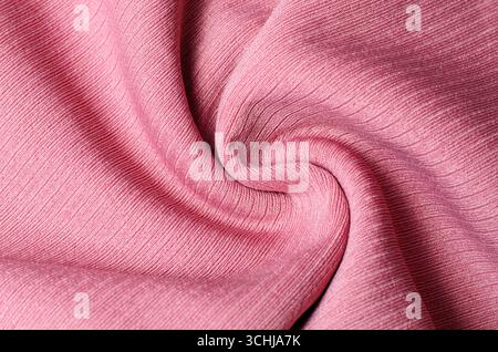 Delicate light pink fabric twisted into spiral shape creating soft textile background for fashion design and elegant decorative concepts Stock Photo
