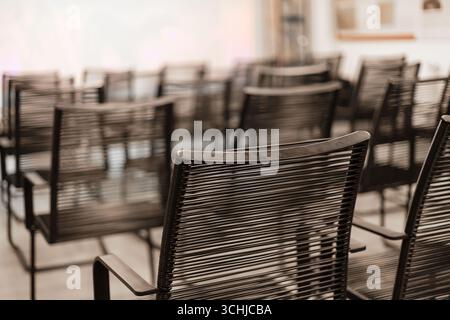 Multiple black chairs are neatly arranged in rows within a bright, modern conference room, waiting for attendees to arrive for an upcoming meeting or Stock Photo