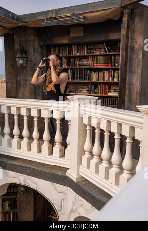 Person on Ornate Balcony with Binoculars at Burning Man Library Stock Photo