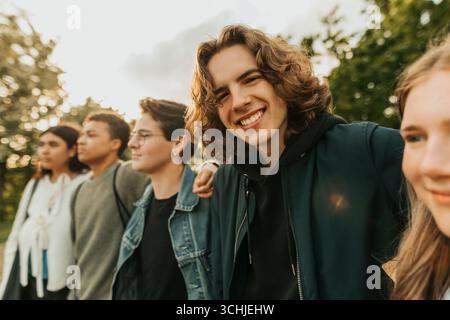 Portrait of smiling long haired young man hanging out with friends Stock Photo