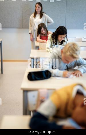 High angle view of students writing while sitting at desk during exam at school Stock Photo