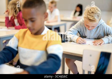 Group of elementary students writing in paper during exam at school Stock Photo
