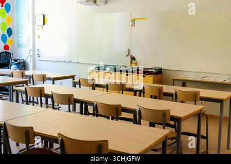 Chairs and tables neatly arranged in empty elementary classroom Stock Photo