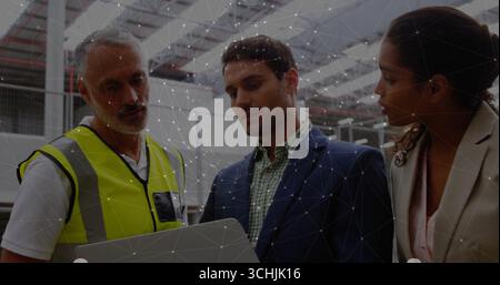 Senior supervisor in neon vest and engineers reviewing tablet in warehouse, with racks and lights Stock Photo