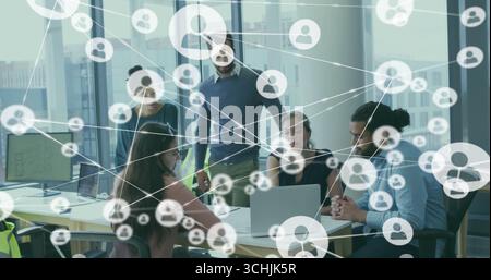Five professionals in business casual attire analyzing network icons on laptop in meeting room Stock Photo