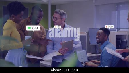 Reviewing data senior man holding tablet and documents in open-plan office, with notification icons Stock Photo