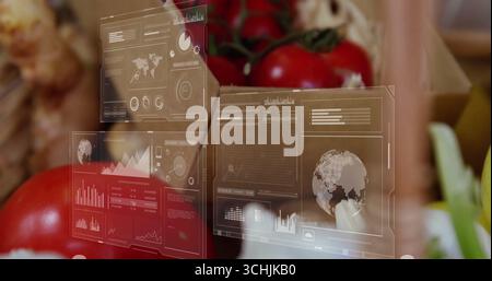 Floating interface panels showing charts over wooden crates at farm stall, with tomatoes and garlic Stock Photo