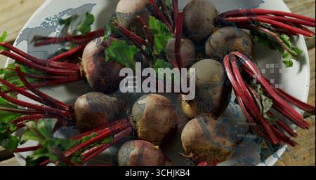 Displaying white bowl of red-stem beetroots and leaves on wood table with world map overlay Stock Photo