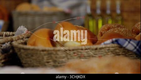 Displaying wicker baskets holding bread rolls on countertop in bakery, with oil bottles and cloth Stock Photo