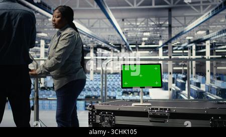 Data center IT professionals check AI dashboard using isolated screen tablet. Server room developers test artificial intelligence tools on chroma key device to ensure reliable performance, camera A Stock Photo