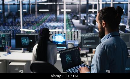 Server room technician using AI LLM chatbot to review infrastructure diagnostics. IT expert in data center using artificial intelligence large language model to analyze performance data, camera A Stock Photo