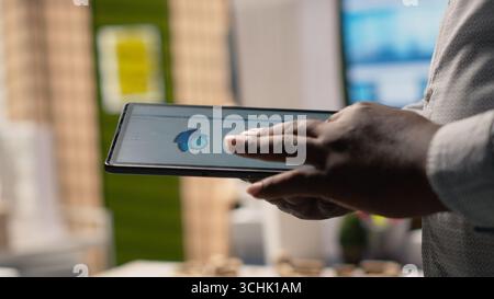 Close up of black professional uses architectural software on tablet to create plan for a smart city infrastructure, focusing on property construction, investment and zoning regulations. Stock Photo