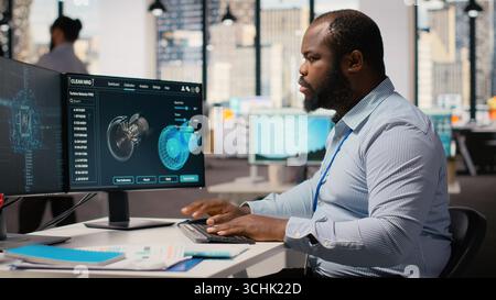 Engineer working on wind turbine simulation in office using artificial intelligence. RD department worker using AI tech and CAD program, doing renewable energy generation engineering, camera B Stock Photo