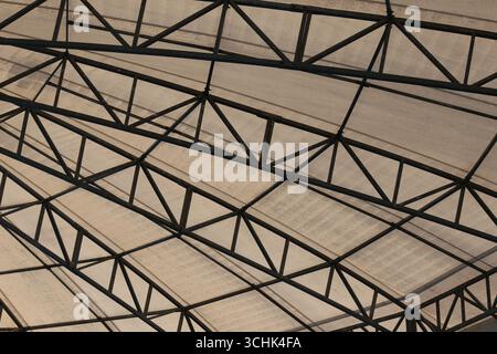 A close-up view of an industrial roof structure featuring a complex metal framework and transparent panels, showcasing modern architectural design. Stock Photo
