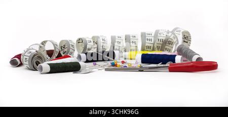 collection of sewing supplies arranged on a white background. Measuring tape, Thread spools, sewing pins, Safety pins, safety pins, scissors Stock Photo
