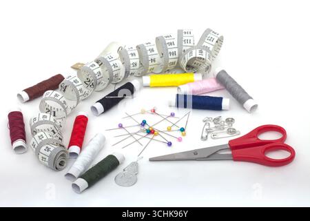 collection of sewing supplies arranged on a white background. Measuring tape, Thread spools, sewing pins, Safety pins, safety pins, scissors Stock Photo
