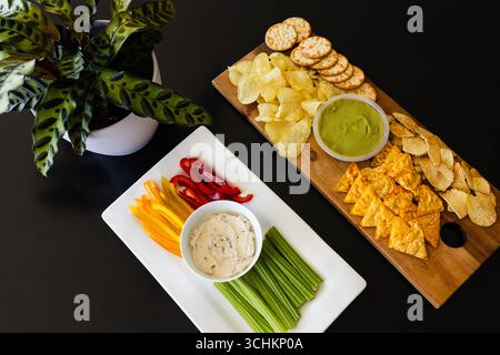 Colorful vegetable platter and chips with dips on table for party celebration, at home Stock Photo