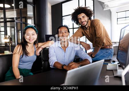 Diverse business team collaborating at office desk, smiling and confident Stock Photo