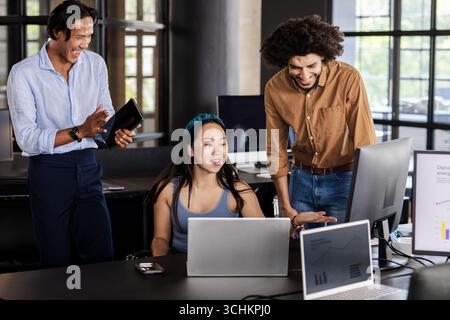 Diverse business team collaborating on project with laptops and digital charts, at office Stock Photo
