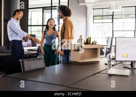 Diverse colleagues discussing project in modern office with charts on computer screens Stock Photo