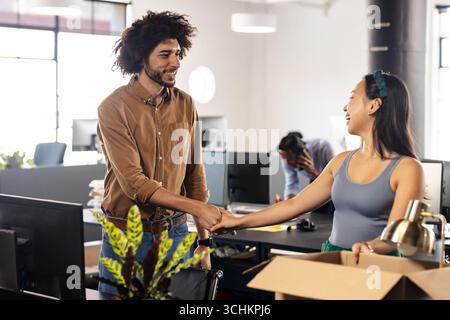 Diverse colleagues shaking hands in modern office, smiling and building teamwork Stock Photo
