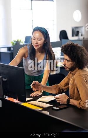 Diverse colleagues collaborating at office, discussing project details on computer screen Stock Photo
