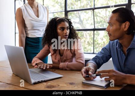 Diverse business team discussing project at office table with laptop and notepad Stock Photo