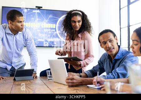 Diverse business team collaborating on project with laptops and tablets in office Stock Photo