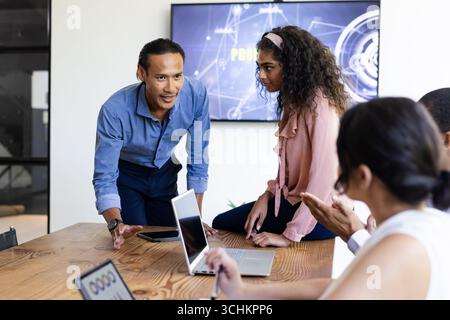 Diverse business team collaborating on project with laptops in modern office Stock Photo