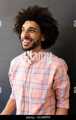 Smiling man in plaid shirt looking away, feeling confident, at office Stock Photo