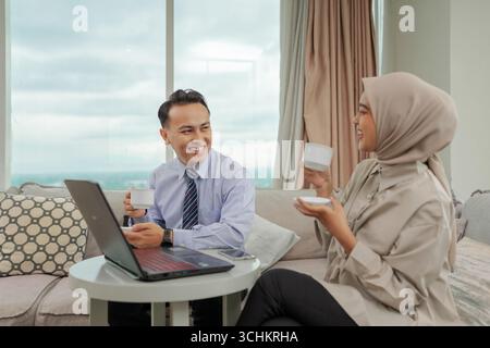 Young Professionals Engaged in Conversation with Laptop at Modern Office Stock Photo