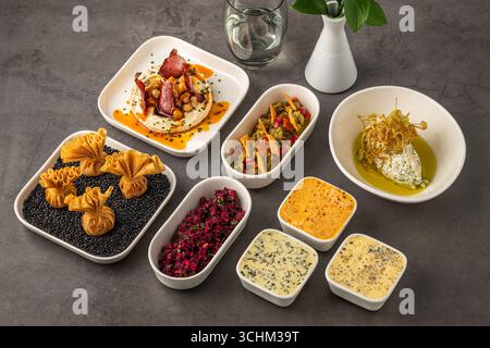 Assorted appetizers with dips, spreads, and vegetables on table Stock Photo