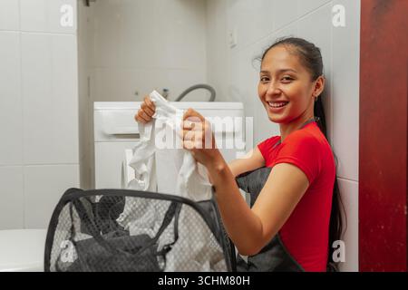 Joyful Young Woman Engaging in Laundry Tasks Within a Modern Home Environment Stock Photo