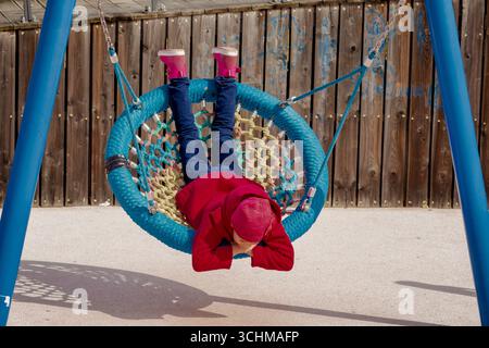 Caucasian smiling child of 8 9 years swinging on round seesaw looking at camera Stock Photo