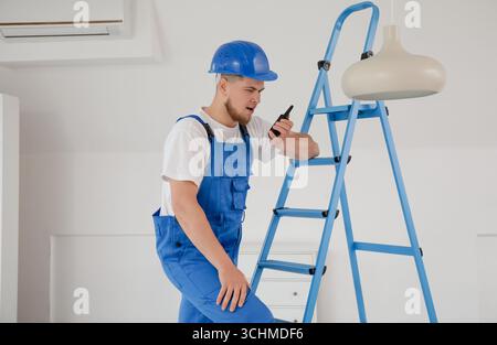 Male contractor talking on radio transmitter in room Stock Photo