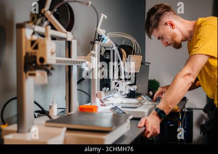 Young designer engineer using a 3D printer in the laboratory and studying a product prototype, technology and innovation concept Stock Photo