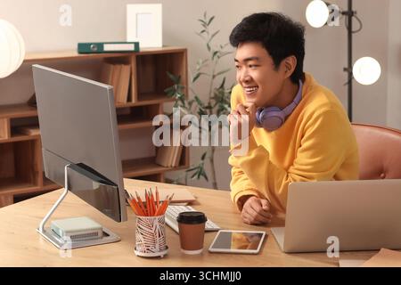 Male Asian programmer working at table in office Stock Photo