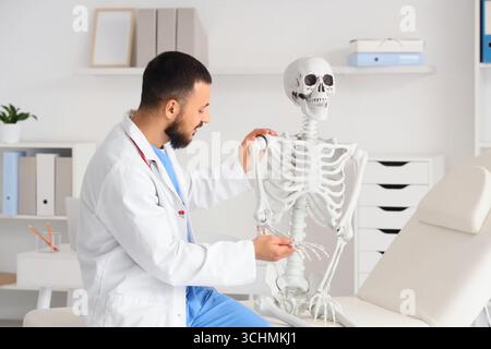 Male doctor examining human skeleton model on couch in clinic Stock Photo